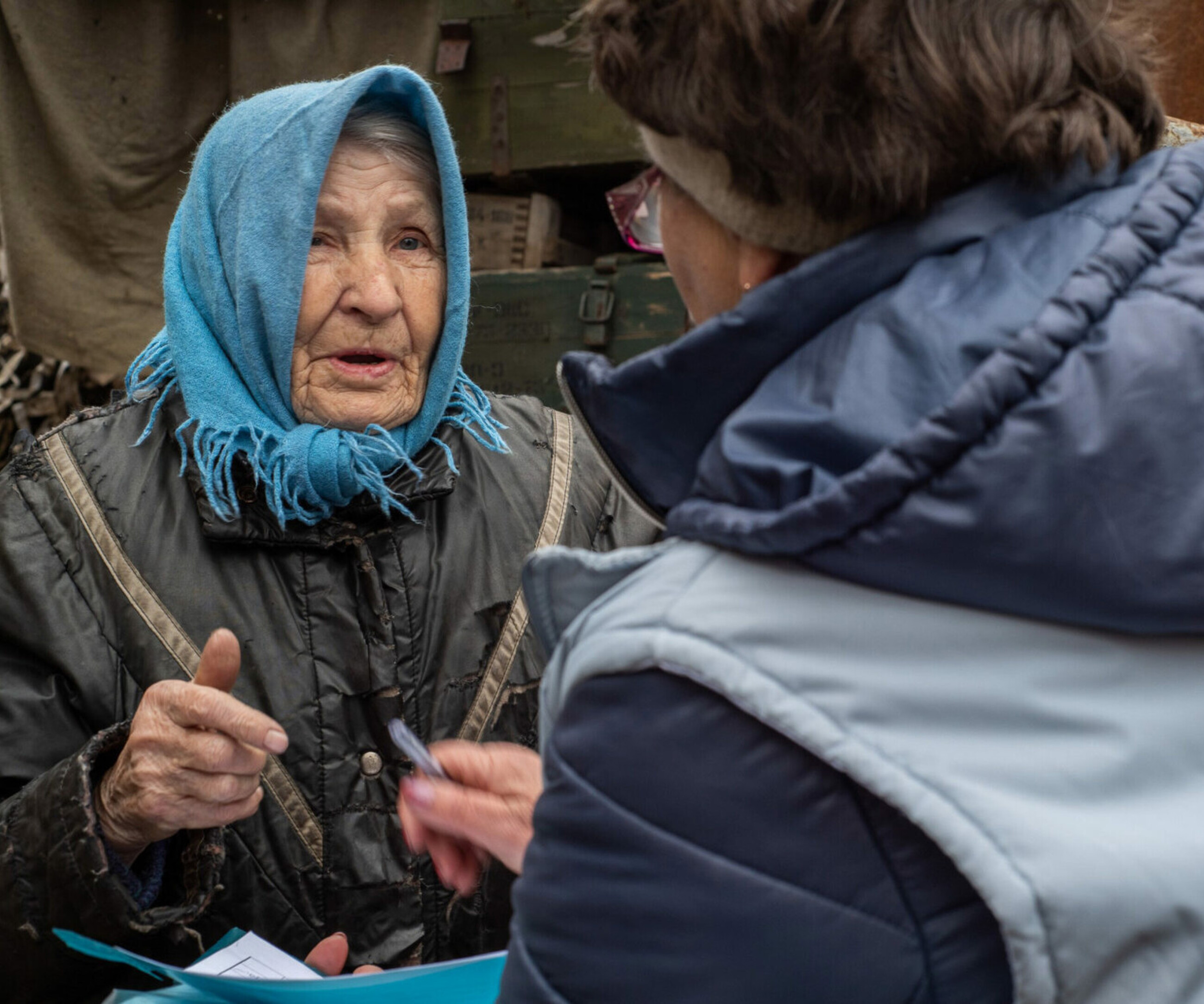 Eine ältere Frau in der Ukraine erzählt einer Mitarbeiterin von HelpAge, was sie benötigt.