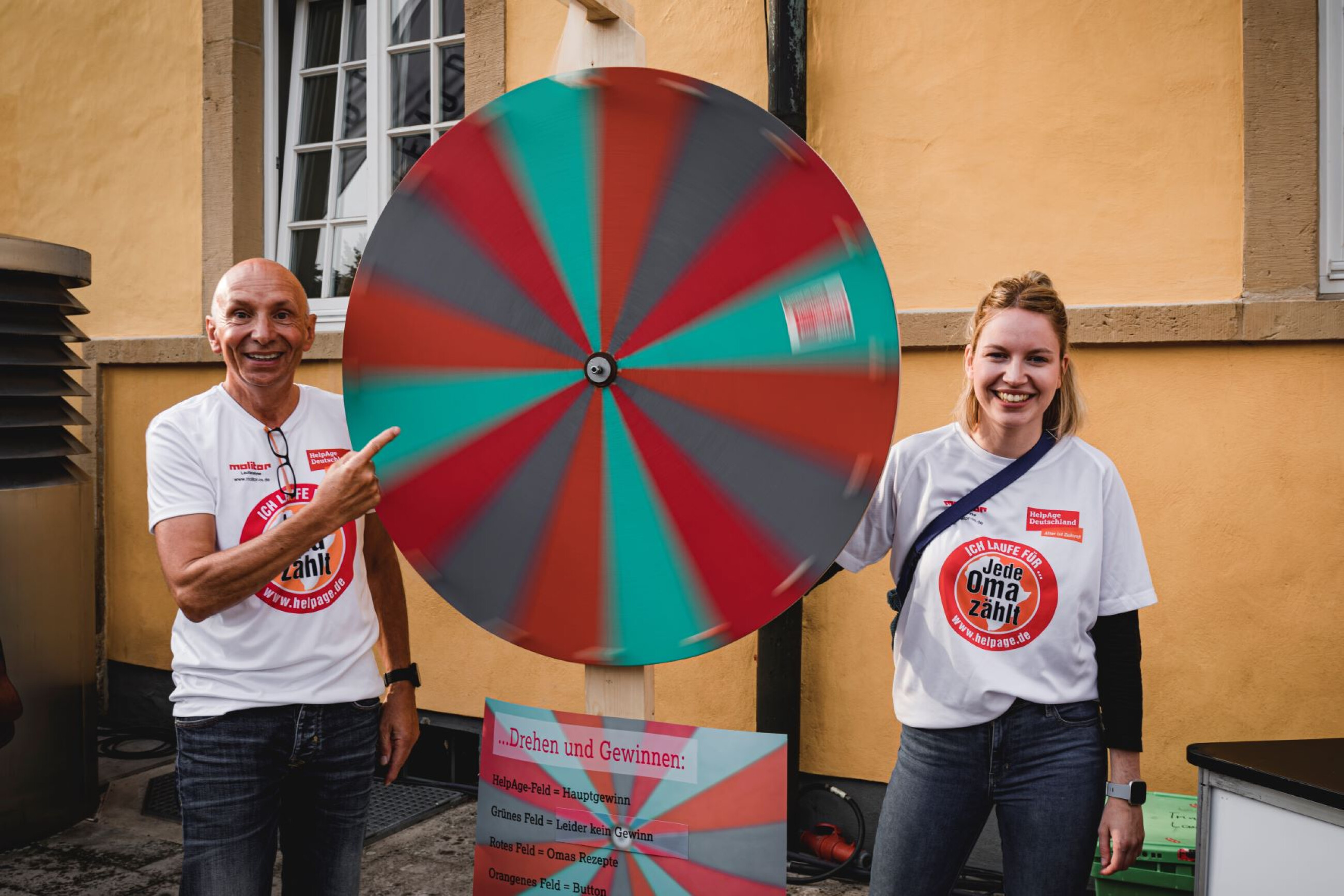 Zwei Personen stehen neben einem drehendem Glücksrad